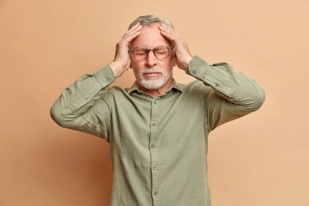 Homem com Alzheimer precoce coloca as mãos na cabeça.