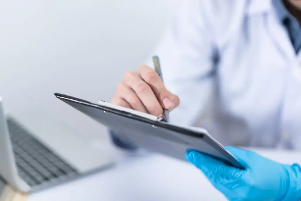 Consulta com o clínico geral. Imagem mostra um profissional de saúde fazendo anotações em um tablet.