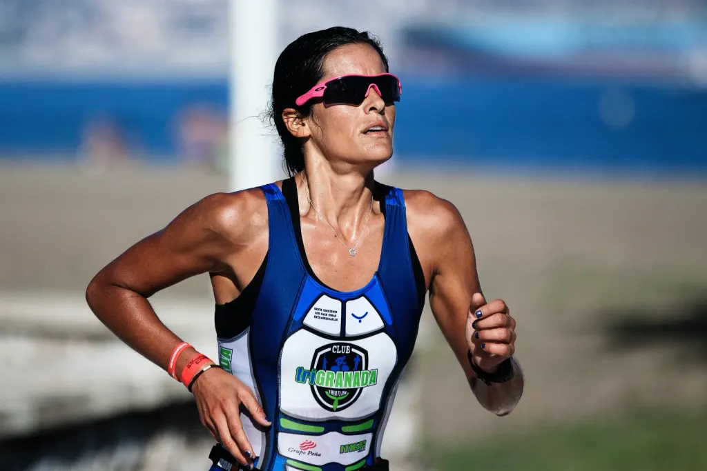 Mulher correndo em pista de corrida. A imagem representa lesões musculares.